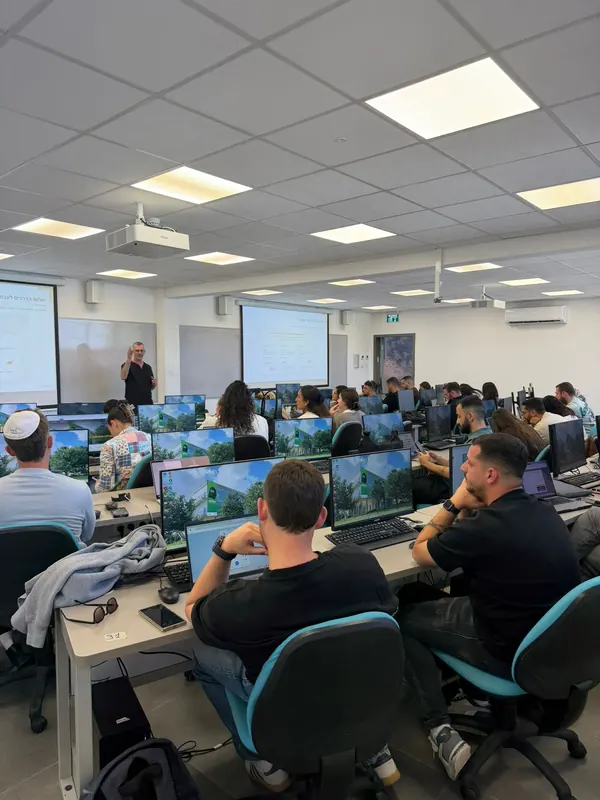 סדנת AI בכיתת מחשבים גדולה, דניאל נחמיה מציג מול המשתתפים