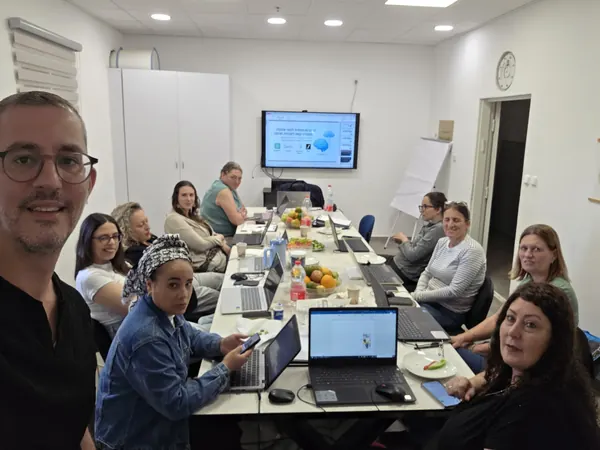דניאל נחמיה עם קבוצת משתתפות בסדנת AI סביב שולחן העבודה